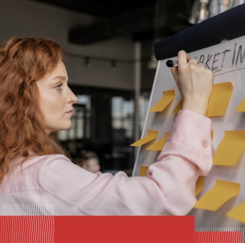 Red haired women at a white board with yellow post-its