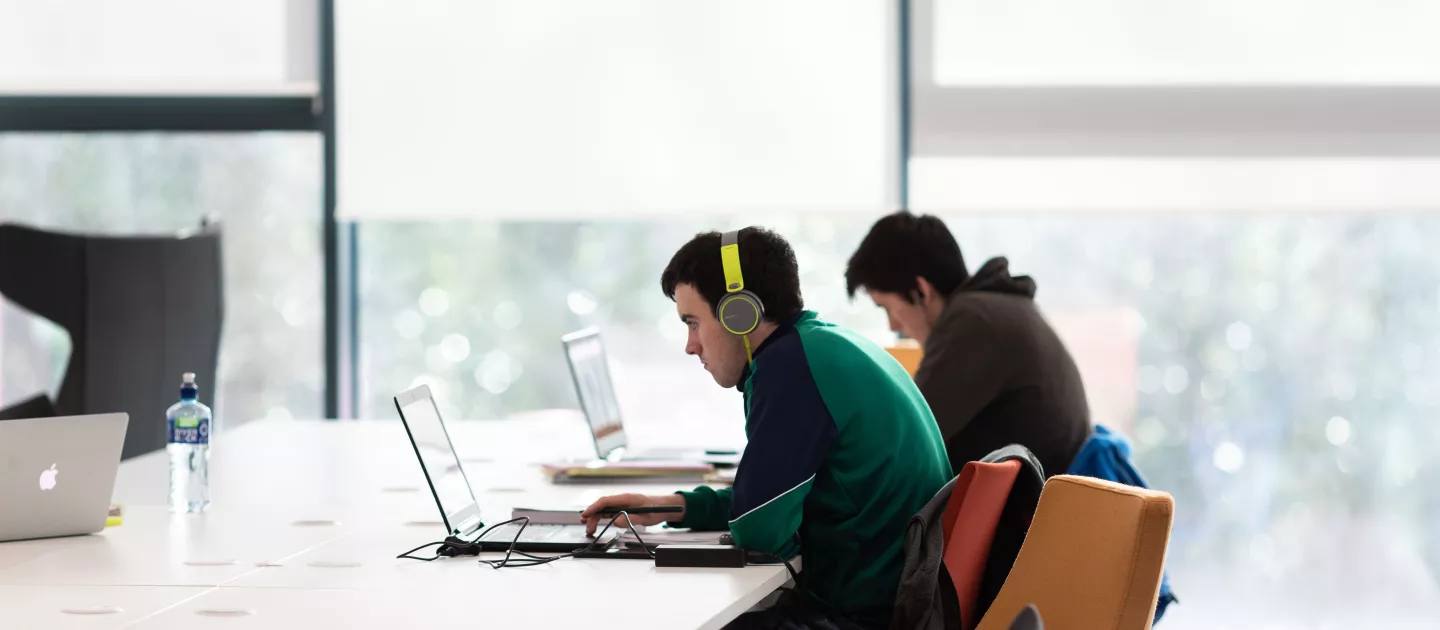 2 students on laptops in the library