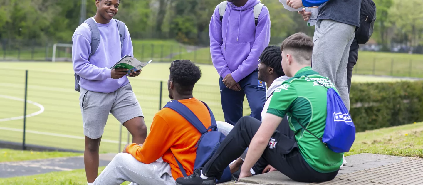 group of young men sitting on grass and chatting