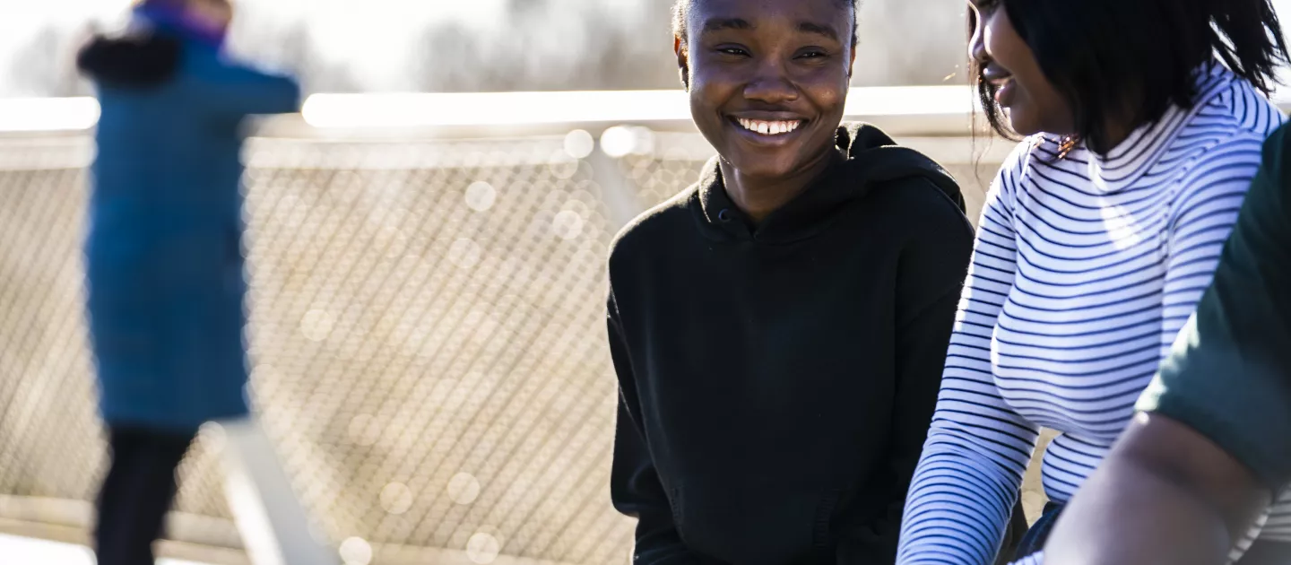 Two female students smiling and talking, while sitting on the UL Living Bridge