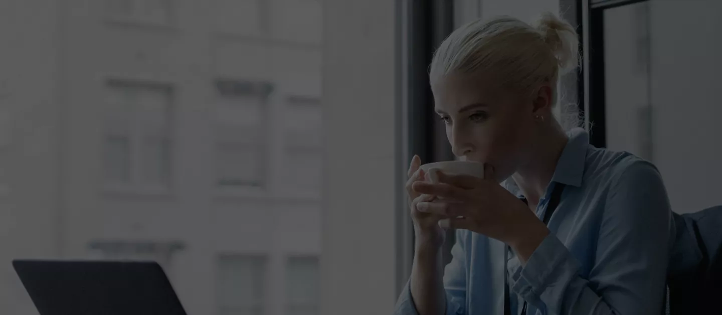 Women at her desk drinking a coffee