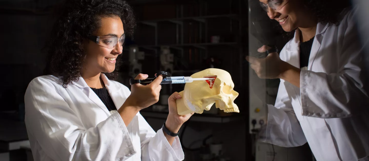 Student syringing into a skull figure