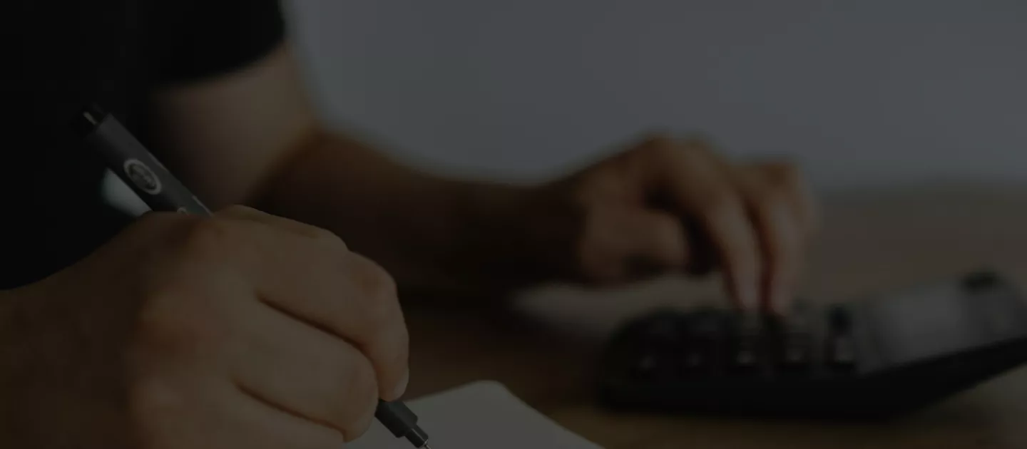 close up of hands writing and using a calculator