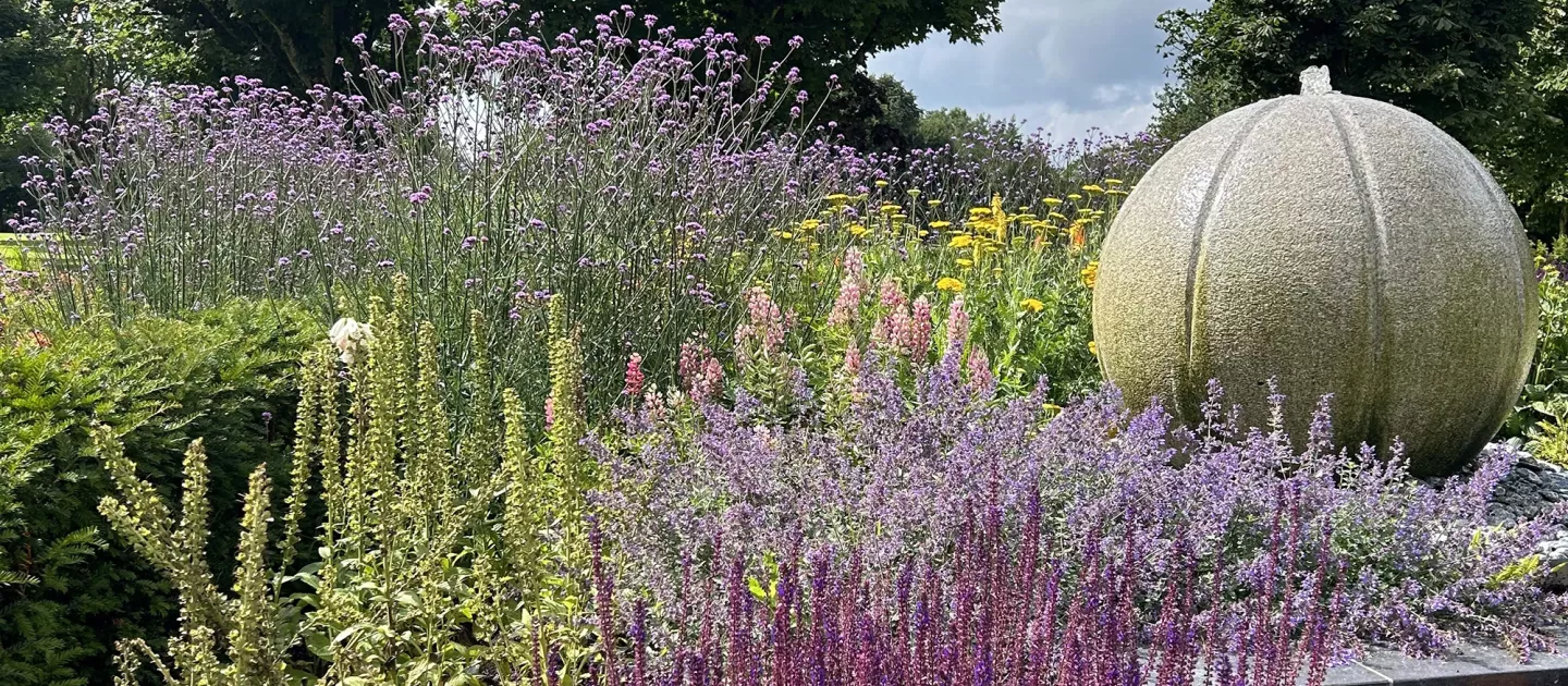 a garden with flowers and a circular stone sculpture