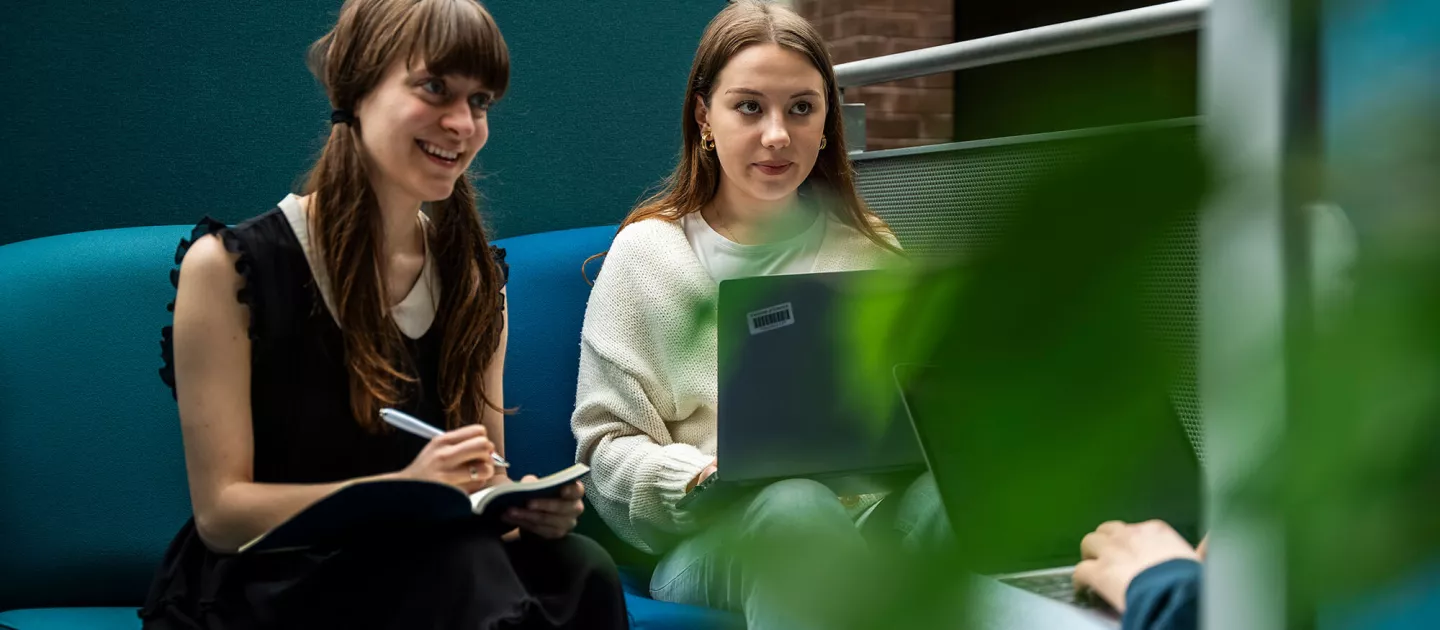 two female students studying and smiling on a couch