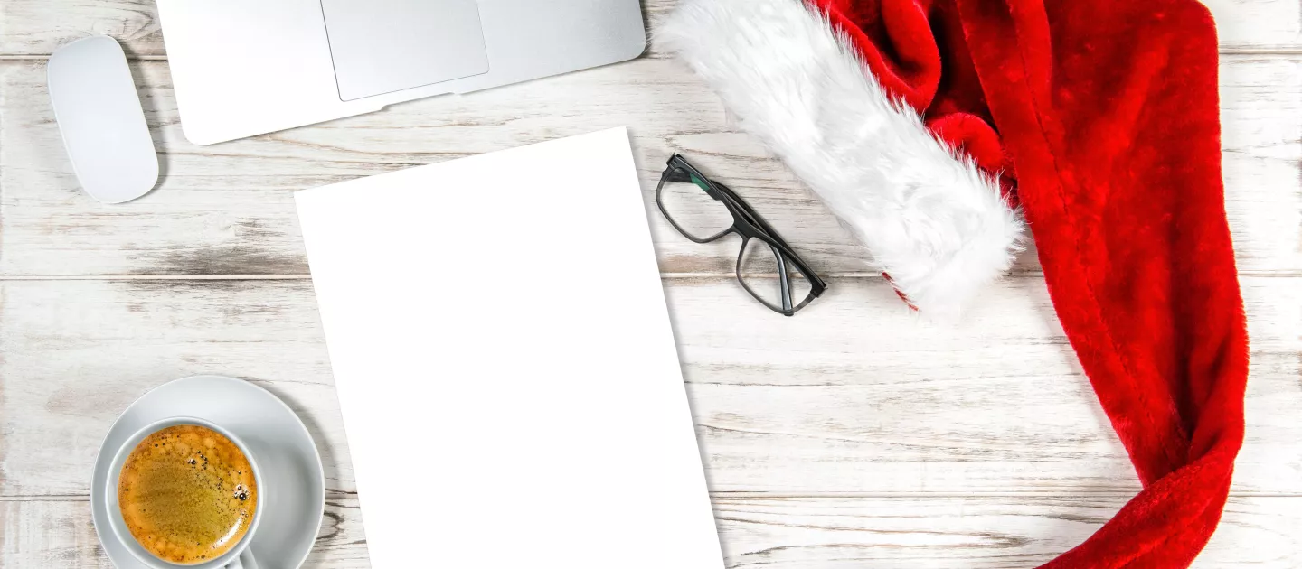 Red and White Santa hat, laptop keyboard, mouse, coffee cup, glasses and notepad 