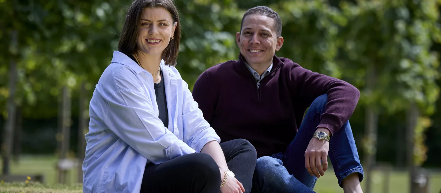 two postgraduate students sitting together on grass 