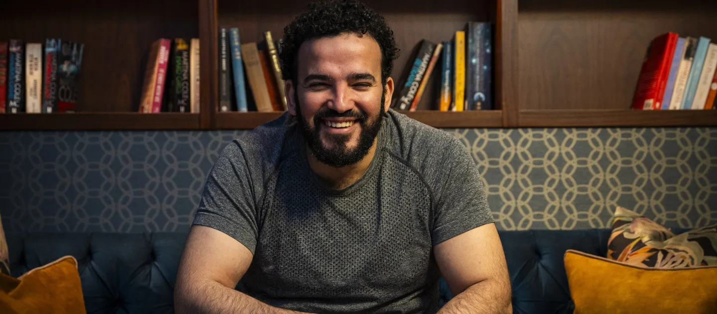 man sitting on a sofa smiling at the camera 