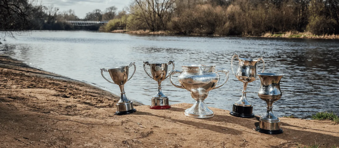 5 GAA trophies on the banks of the river Shannon with the UL Living Bridge in the background