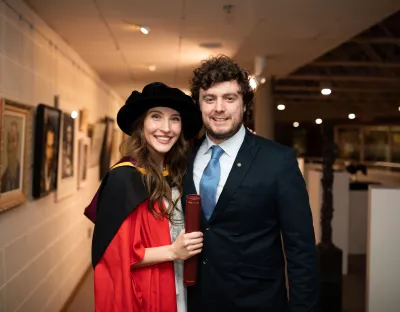 A student in Doctorate Robes embraces a man