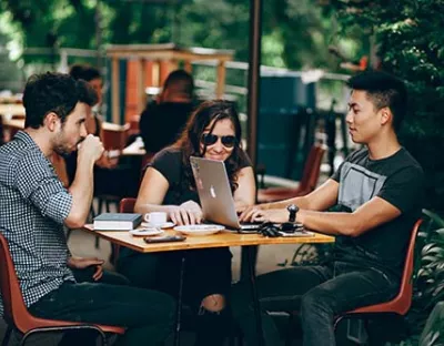 Students sitting around a table with a mac