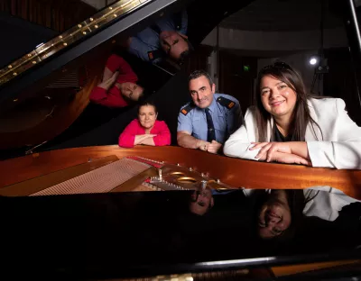 Three people at a piano in the Irish World Academy at UL