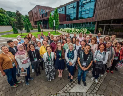 A group of circa 40 men and women with conference delegate lanyards outside the UL Glucksman Library Extension