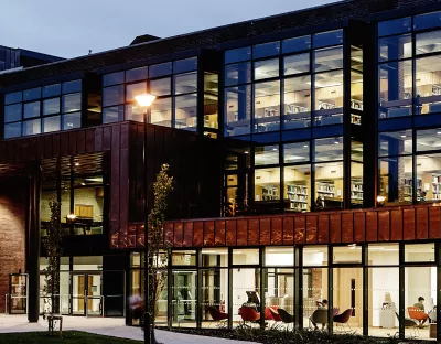 Library building lit up at evening with people