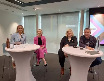 Four attendees of the event pictured sitting at two tables