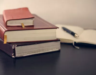 pile of three books with open notebook in background