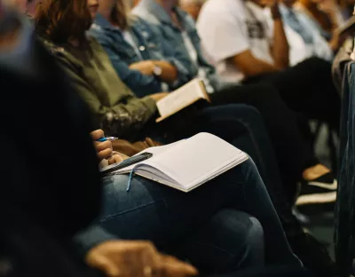 close up shot of people taking notes in an audience