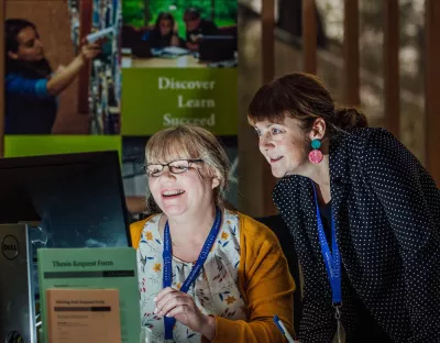 2 Library staff members collaborating over a computer screen