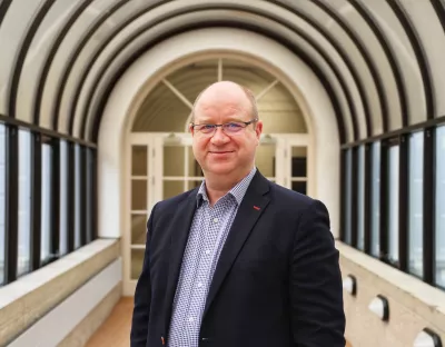 Head and shoulders colour photograph of Professor Kenneth Stanton.  He is wearing a blue shirt and navy jacket looking directly at the camera.