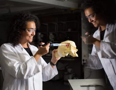 Student syringing into a skull figure