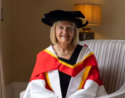 A picture of Professor Brigid Laffan in her robes, sitting in a chair