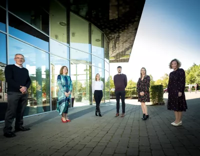 Group of people standing outside in front of a large glass building