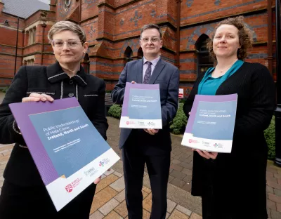 A picture of three academics holding copies of their research