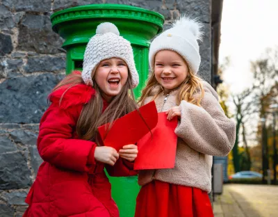 An image of two girls in front of a post box with their Santa letters