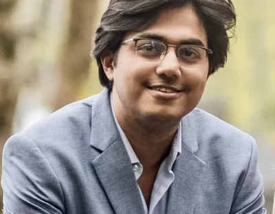 A man with dark hair wearing glasses smiling