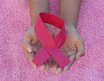 Cupped hands holding pink looped ribbon