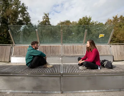 two students sitting on a bench and talking