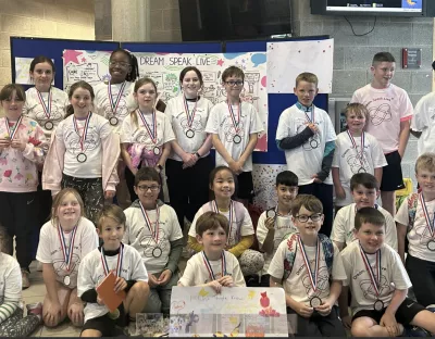 Group of children wearing which tshirt and medals in a classroom