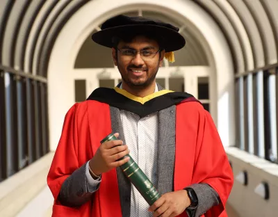 A picture of Dr Bikash Guha from Athenry in Co. Galway became the first apprentice graduate of the Professional Doctorate in Engineering (PDEng) programme at UL. He is wearing conferring robes and holding a parchment in a tunnel at UL