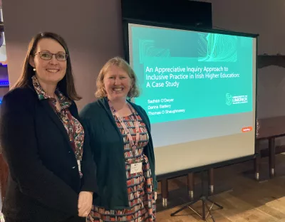 Darina Slattery and Sadhbh O'Dwyer smiling and standing beside a projection screen that shows the title of their presentation 'An Appreciative Inquiry Approach to Inclusive Practice in Irish Higher Education: A Case Study'.