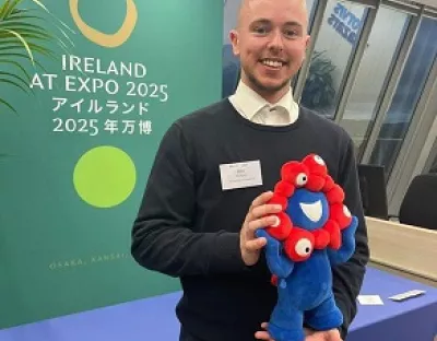 Ben Murphy smiling at the seminar holding the mascot of the EXPO, whose name is Myaku Myaku.