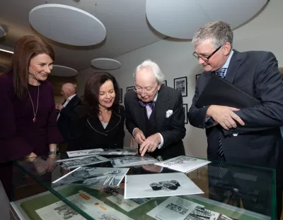 Four people looking at old photographs on top of a glass case - they are in the UL library