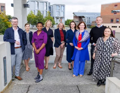 A group of nine people gathered for photograph standing outside on university campus