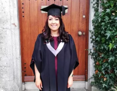 Picture of a woman in graduation robes smiling for photo