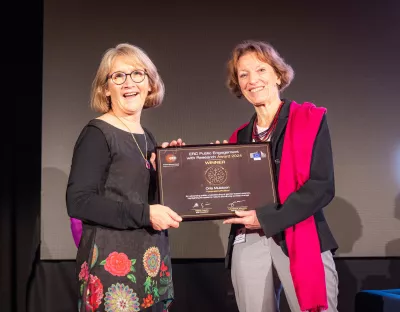 Picture of two women smiling and holding an award on a stage