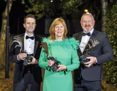 A picture of three people together holding awards - they are in black tie attire