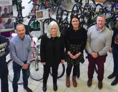 A photo of a group of people - three men and three women - standing in front of a row of bikes