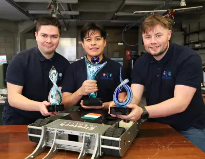 Three students pictured at UL with a robot they designed