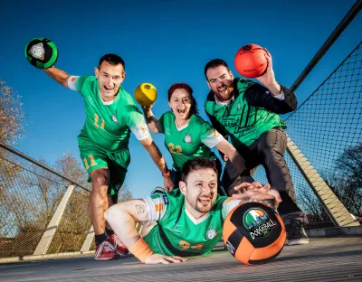 Four dodgeball athletes wearing Irish dodgeball team jerseys pose for a photo on the living bridge in University of Limerick