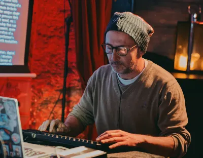 Man typing on computer keyboard in front of laptop with screen in background