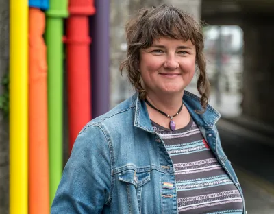 Singer in denim jacket in front of colourful background