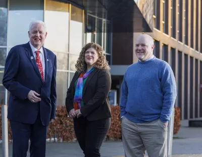 woman and two men standing in front of building