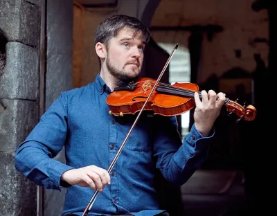 Musician sitting down playing the fiddle