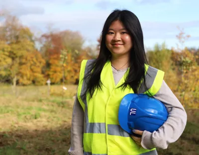 A picture of Madissen Cayla Ashlee Pangestu wearing a high vis vest and holding a blue hard hat