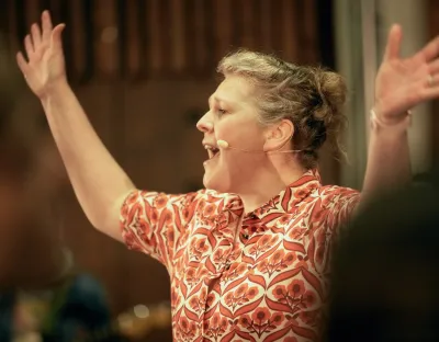 Kathleen Turner conducting choir members