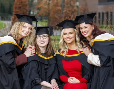 A picture of four students in graduation robes on the UL campus